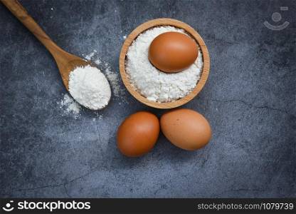Homemade flour eggs cooking ingredients on kitchen table / Pastry flour on wooden bowl on gray background , top view