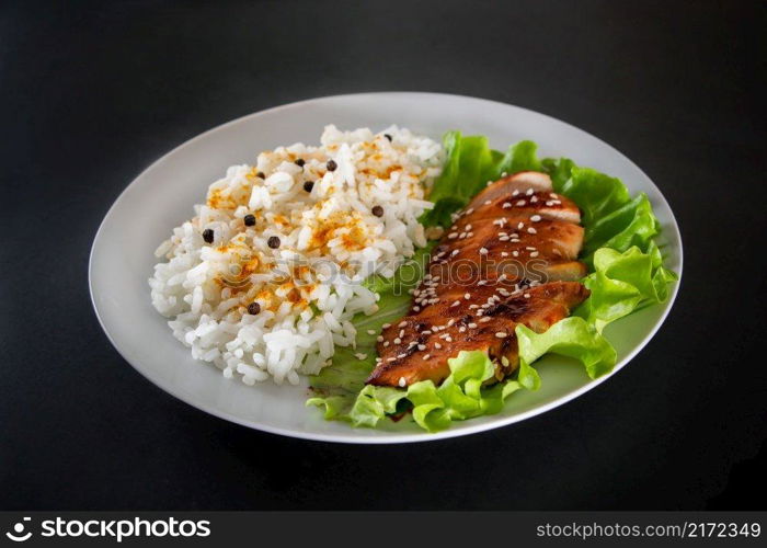 Homemade food - teriyaki chicken with white rice and pepper on a black background.