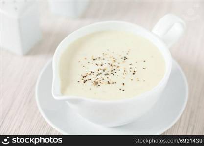 Homemade French Bechamel or White Sauce served in sauce boat, photographed with natural light (Selective Focus, Focus in the middle of the image). Bechamel or White Sauce
