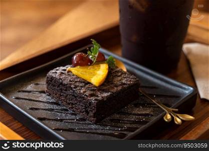 Homemade fresh baked delicious chocolate and chocolate orange brownies and Americano iced coffee or black coffee in wood desk office desk in coffee shop at the cafe in garden,during business work