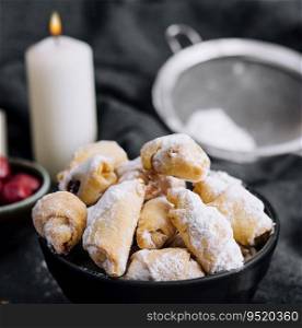 Homemade fresh cookies dusted powdered sugar in black bowl