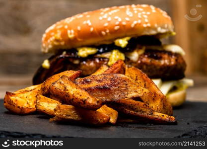 Homemade fresh tasty cheese burger and fried potatoes on a wooden table