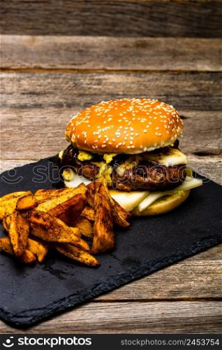 Homemade fresh tasty cheese burger and fried potatoes on a wooden table