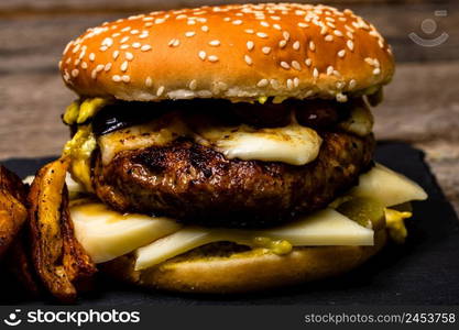 Homemade fresh tasty cheese burger and fried potatoes on a wooden table