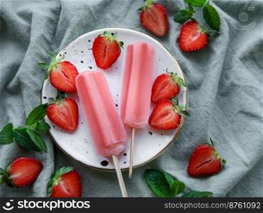 Homemade frozen strawberry ice cream popsicles and fresh strawberries. Summer dessert