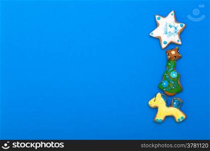 Homemade gingerbread cake pony christmas tree and star with icing and colorful decoration on blue as frame background. Holiday handmade decoration concept.