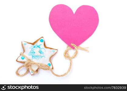 Homemade gingerbread cake star with icing and blue decoration and pink heart love symbol on white as christmas background. Holiday handmade concept.