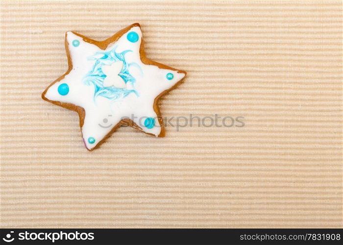 Homemade gingerbread cake star with icing and blue decoration on brown as christmas background. Holiday handmade concept.