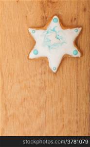 Homemade gingerbread cake star with icing and blue decoration on wooden board as christmas background. Holiday handmade concept.