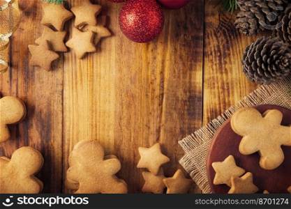 Homemade gingerbread men cookies and christmas decoration on rustic wooden background with copy space. Table top view frame