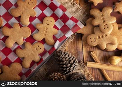 Homemade gingerbread men cookies on rustic wooden table, traditionally made at Christmas and the holidays. Flat lay table top view.