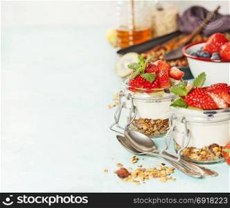 Homemade granola muesli with nuts and dried fruits and yogurt in glasses on rustic wooden background. Healthy breakfast.