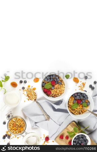 Homemade granola (with dried fruit and nuts) and healthy breakfast ingredients - honey, milk and berrieson white background