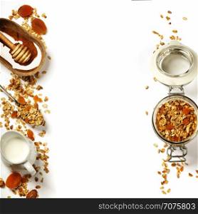 Homemade granola (with dried fruit and nuts) and healthy breakfast ingredients - honey, milk and fruits on white background