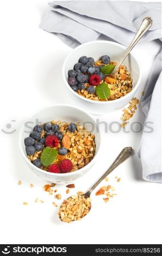 Homemade granola (with dried fruit and nuts) and healthy breakfast ingredients - honey, milk and berries on white background