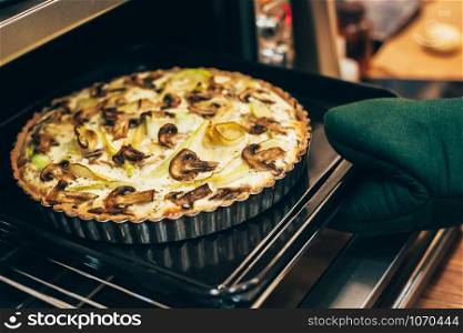 Homemade healthy gluten free vegan quiche pie with mushrooms and squash baking in hot oven for autumn holiday dining. Cozy home mood. Diet food cooking