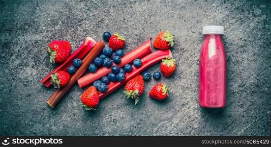 Homemade healthy refreshing fruit beverages in bottle with ingredients. Red berries and fruits smoothie, juicy vitamin drink on gray concrete background , top view. Food concept