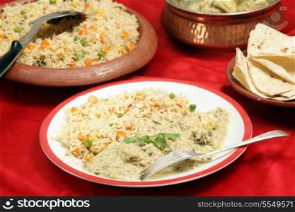 Homemade, indian-style dinner of fish in green curry sauce served with three-coloured vegetable pilau rice and a plate of chappatis.