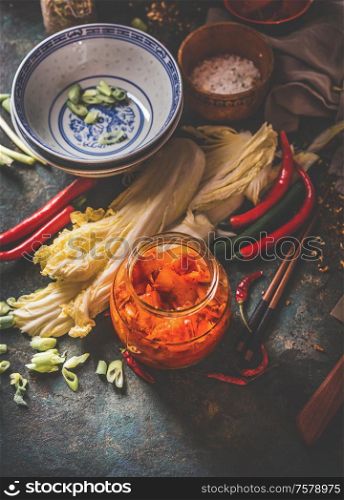 Homemade kimchi preparation. Fermented chinese cabbage marinated in hot chili sauce in jar on rustic background with ingredients. Top view. Healthy asian food