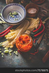 Homemade kimchi preparation. Fermented chinese cabbage marinated in hot chili sauce in jar on rustic background with ingredients. Top view. Healthy asian food