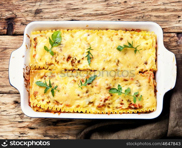 Homemade lasagna on wooden table. Traditional italian lasagne food, in a baking dish