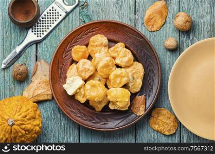 Homemade lazy dumplings with pumpkins on an old wooden table. Pumpkin dumplings lazy