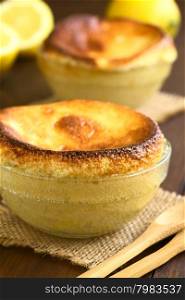Homemade lemon souffle in glass bowls, photographed on dark wood with natural light (Selective Focus, Focus on the front of the first souffle)