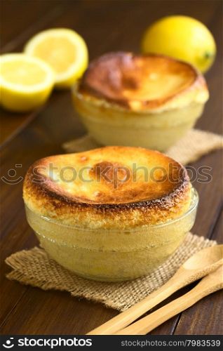 Homemade lemon souffle in glass bowls, photographed on dark wood with natural light (Selective Focus, Focus on the front of the first souffle)