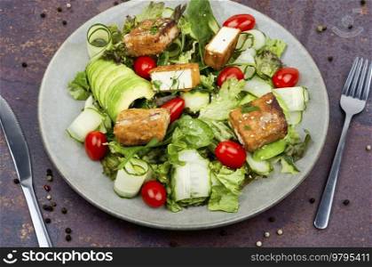 Homemade lettuce salad with cucumber, avocado and fried tofu soy cheese. Healthy lifestyle. Salad of fried tofu and fresh vegetables.