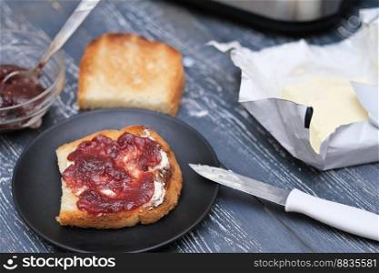 homemade marmalade berry jam on a toast with butter. wooden table in country kitchen. simple breakfast. . homemade marmalade berry jam on a toast with butter. wooden table in country kitchen. simple breakfast