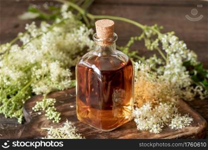 Homemade meadowsweet tincture with fresh blooming plant on a table
