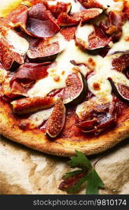 Homemade meat pizza with cheese and figs.. Appetizing pizza with bacon and fruit.
