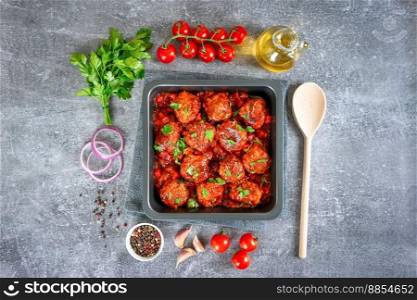 Homemade meatballs with tomato sauce and spices served in black pan on grey concrete background. Tasty cooked meat balls made with minced beef and food ingredients. Top View, Flat lay.. Homemade meatballs with tomato sauce and spices served in black pan on grey concrete background