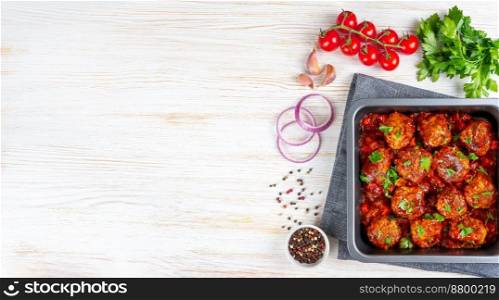 Homemade meatballs with tomato sauce and spices served in black pan on white background. Tasty cooked meat balls made with minced beef and food ingredients. Top View, Flat lay, banner with copy space. Homemade meatballs with tomato sauce and spices served in black pan on white wooden background