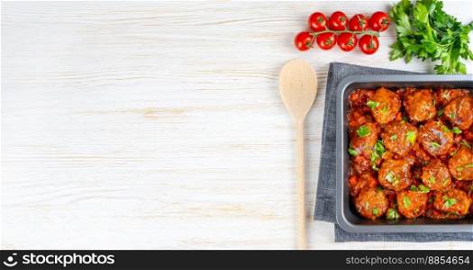 Homemade meatballs with tomato sauce and spices served in black pan on white background. Tasty cooked meat balls made with minced beef and food ingredients. Top View, Flat lay, banner with copy space. Homemade meatballs with tomato sauce and spices served in black pan on white wooden background