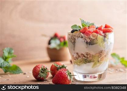 Homemade muesli, bowl of oat granola with yogurt, fresh blueberries, mulberry, strawberries, kiwi, mint and nuts board for healthy breakfast, copy space. Healthy breakfast concept. Clean eating.