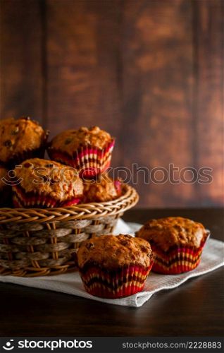 Homemade muffins with raisins on a wooden background. Cupcake in a paper mold on a white napkin.. Muffins with raisins on a wooden background. Cupcake in a paper mold on a white napkin.
