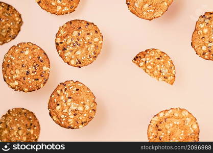 Homemade oatmeal cookies with flax, sunflower and sesame seeds on nude color wallpaper. Healthy fitness food concept. Milk and homemade cookies for breakfast layering on nude color background