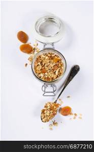 Homemade oatmeal granola with fruits and nuts in a glass jar on white background
