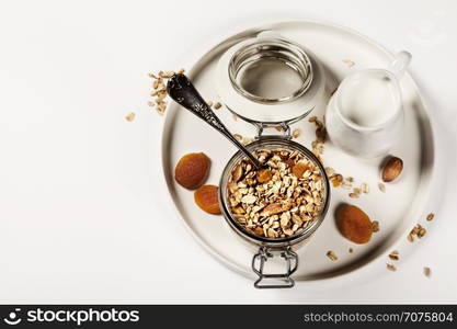 Homemade oatmeal granola with fruits and nuts in a glass jar on white background