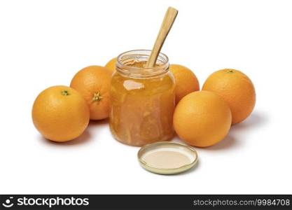 Homemade orange marmelade in glass jar and fresh oranges in the background