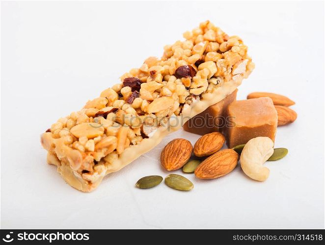 Homemade organic granola cereal bar with nuts and dried fruit on white with oats and raw wheat.