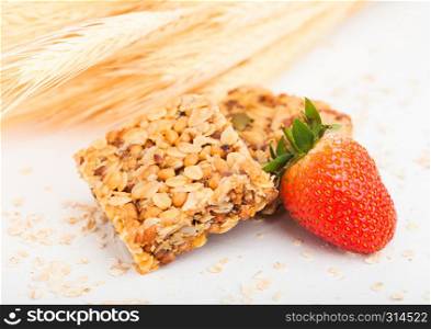 Homemade organic granola cereal bars with nuts and dried fruit on white with oats and raw wheat and strawberry