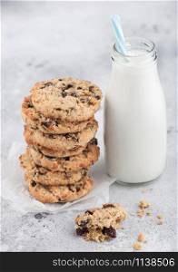Homemade organic oatmeal cookies with raisins and apricots and bottle of milk on light kitchen background.