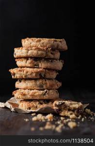 Homemade organic oatmeal cookies with raisins and apricots on dark wood background.