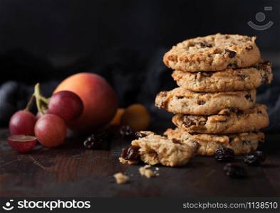 Homemade organic oatmeal cookies with raisins and apricots on dark wood background with apricot and grapes.