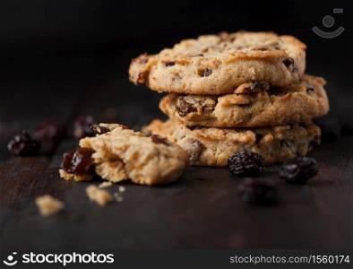 Homemade organic oatmeal cookies with raisins and apricots on dark wood background.