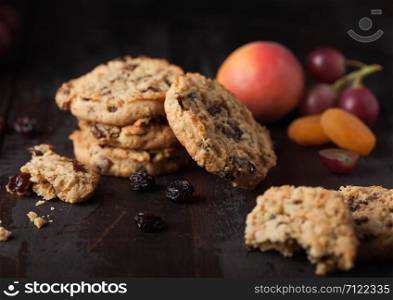 Homemade organic oatmeal cookies with raisins and apricots on dark wood background with apricot and grapes.