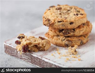 Homemade organic oatmeal cookies with raisins and apricots on wooden board on light background.