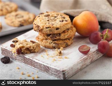 Homemade organic oatmeal cookies with raisins and apricots with baking tray on light kitchen background.